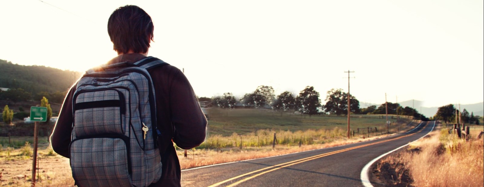 Student with backpack walking down road